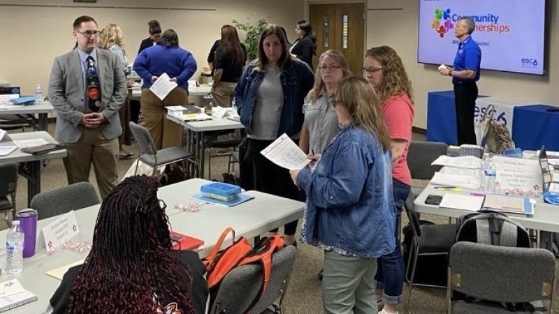 Group of educators standing around a table sharing ideas.